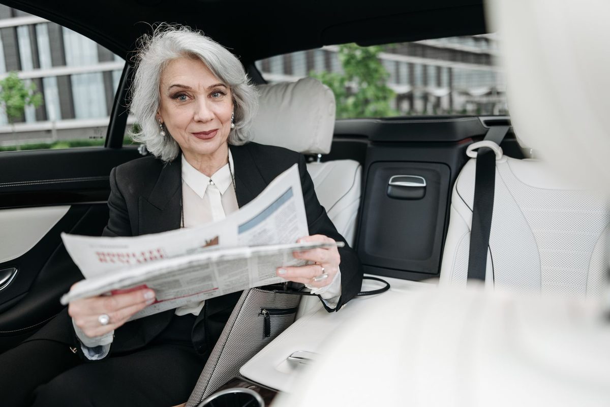 Driver in a car reading a printed auto insurance policy document