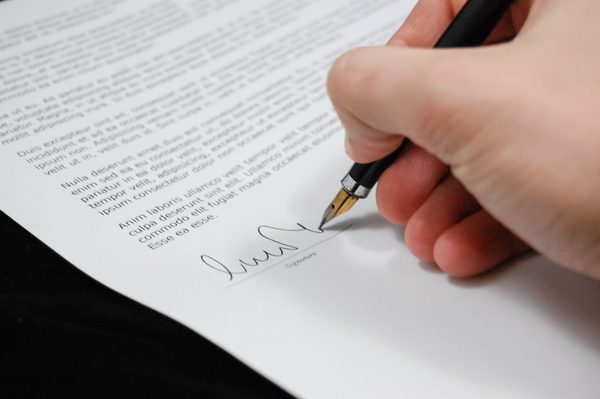 Business owner signing LLC formation documents at a desk