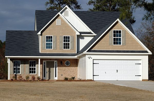 Suburban home exterior alongside homeowners insurance policy paperwork